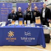 Five people standing behind a table in an Access exhibition area at the Disability Transition Expo